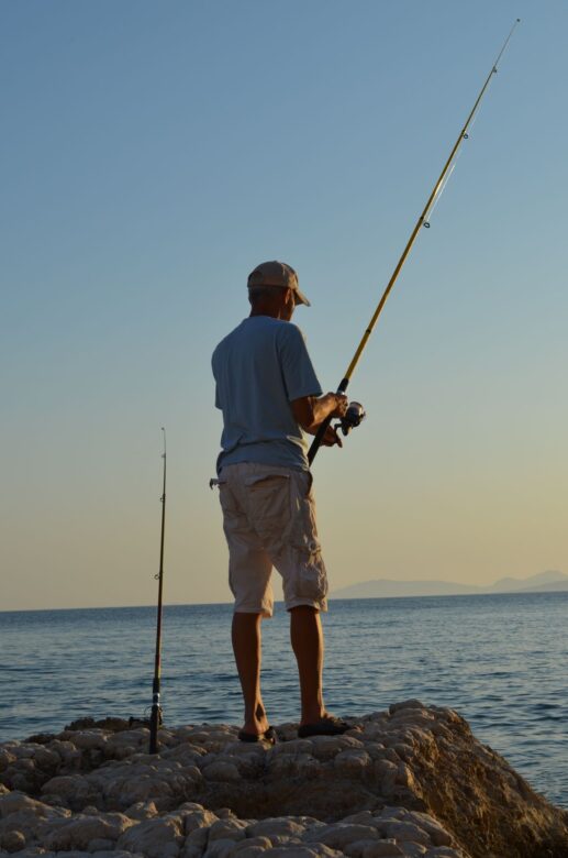 Angler shore jigging from rocks at sunset
