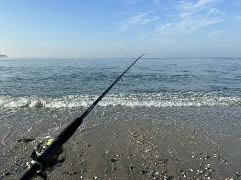 砂浜サーフに構えたショアジギングタックルと朝の海