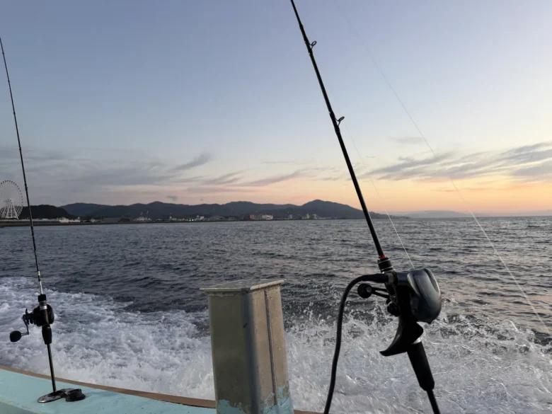 朝焼けの海を走る船上に立てた2本のロッド